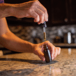 Person taking dropper full of full spectrum CBD oil out of the bottle.
