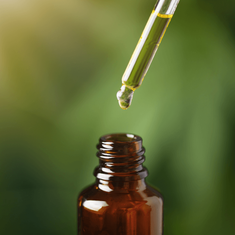 Dropper holding naturally colored full-spectrum CBD oil above an amber bottle