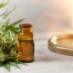 Hemp flower and amber hemp extract beside warm light, representing controlled decarboxylation