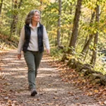 Woman enjoying a walk on a sunlit woodland path in early autumn
