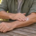 Man gently applying a thin layer of lotion to his forearm after gardening